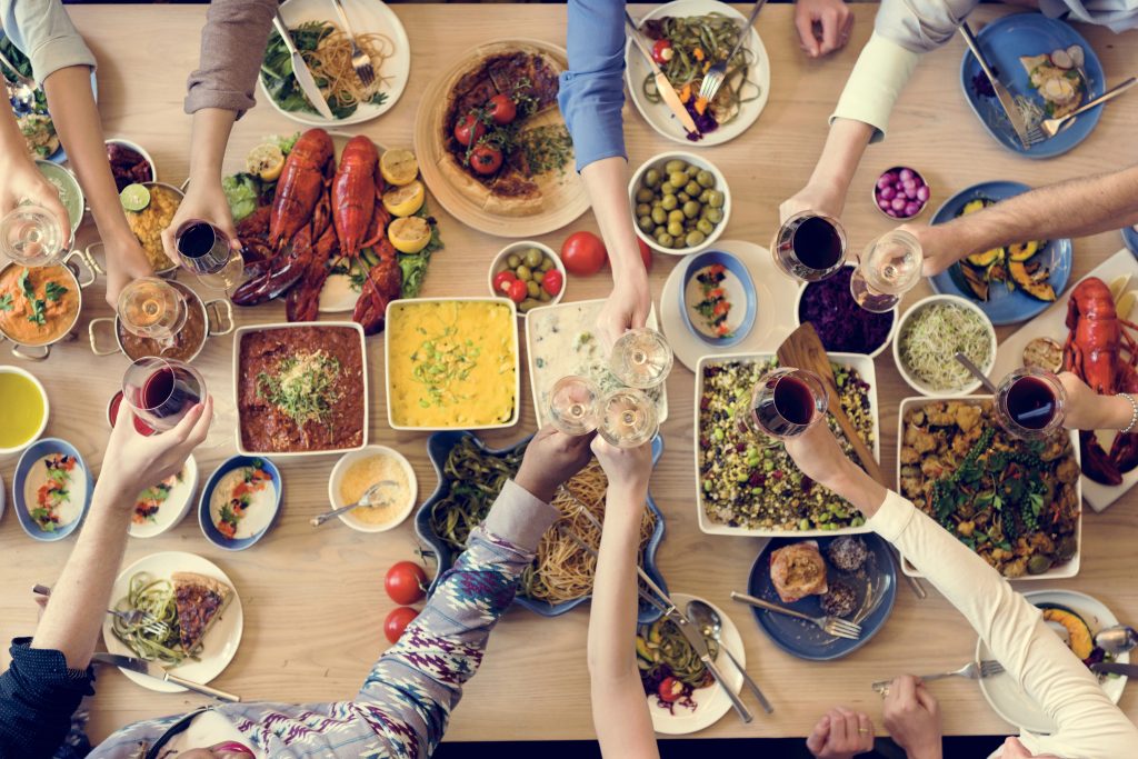 Multiethnic people having a meal and drinks at a large table.